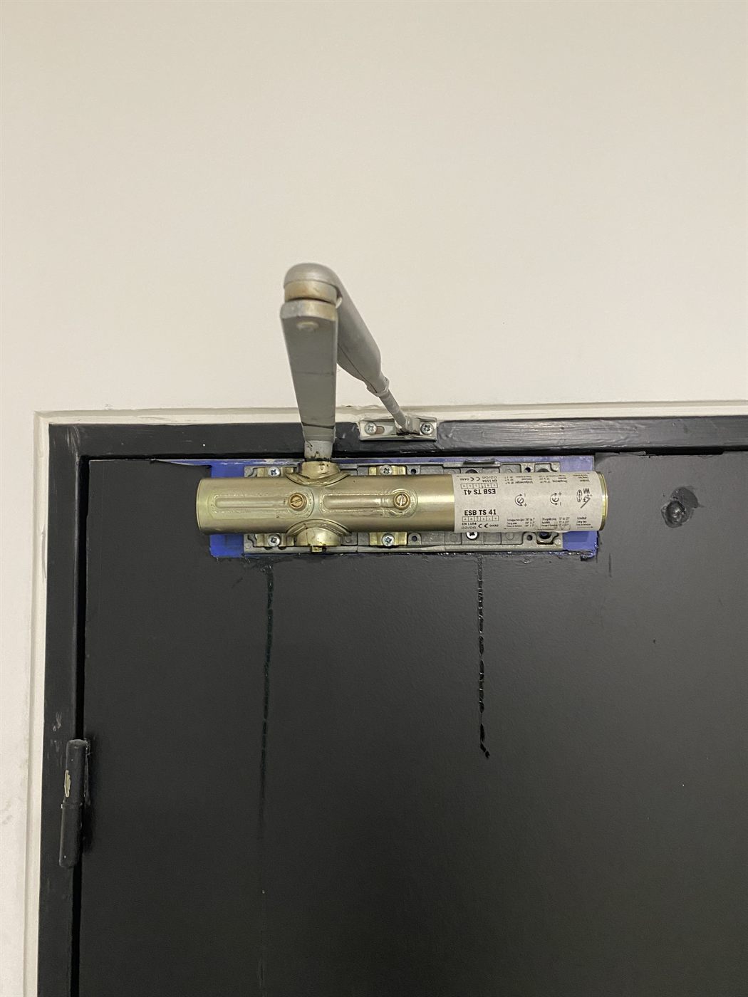 Ancien ferme-porte sur une porte, avant remplacement