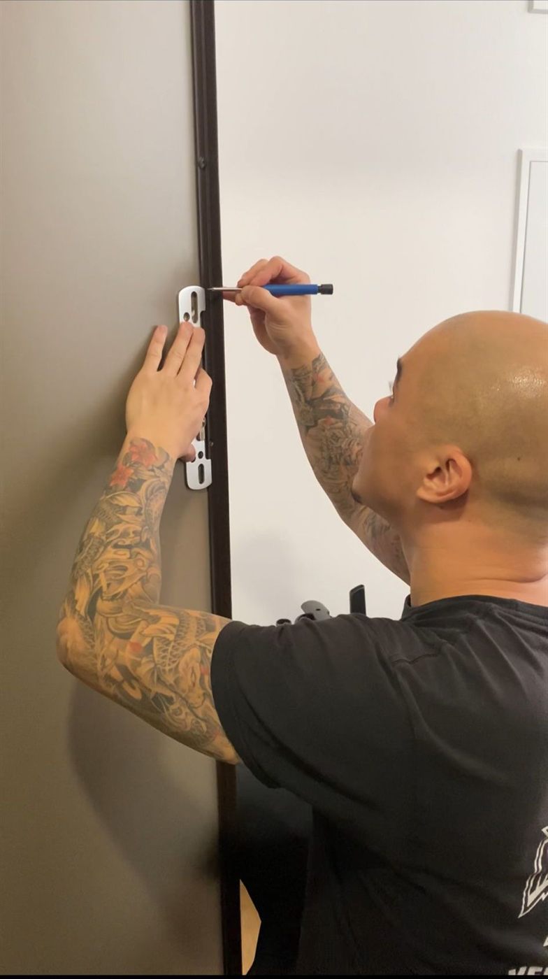 Artisan KAM posant une cornière anti-pince sur une porte